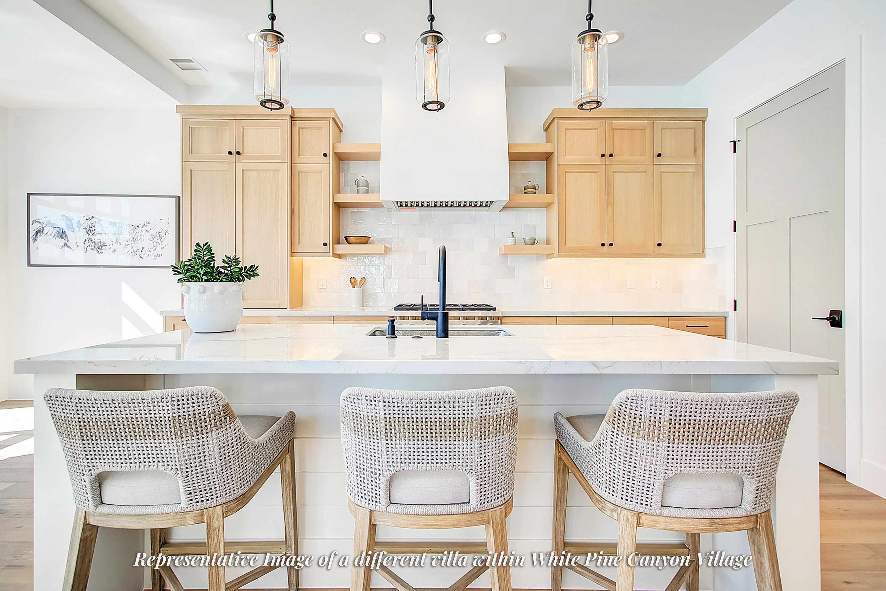 Contemporary kitchen featuring a large island with a substantial countertop, light wood-finish cabinetry, a built-in range hood, white subway tile backsplash, and recessed and pendant lighting