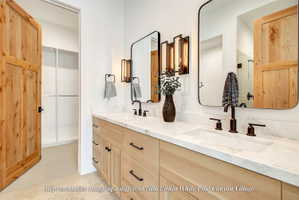 Double vanity with light wood-finish cabinetry, white countertop, and dark-finish hardware