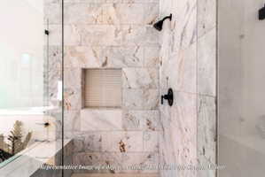Shower enclosure featuring a frameless glass panel, large-format tile walls, matte black shower fixtures, and a recessed niche with penny tile