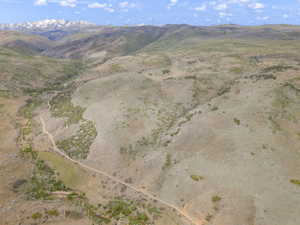 Expansive undeveloped land featuring rolling hills, scattered brush, and a dirt path winding through the terrain