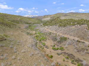 Expansive mountain landscape featuring varied terrain, a winding dirt road, and a stream bed