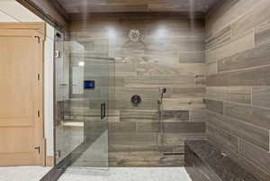 Walk-in shower featuring wood-finish tile walls, glass enclosure, built-in stone bench, and rain shower head