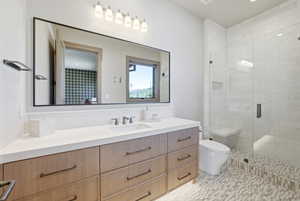 Bathroom featuring a wide wood-finish vanity with ample drawer storage, a white countertop with an undermount sink, and a large rectangular mirror