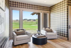 Room featuring floor-to-ceiling windows, wood-finish flooring, and plaid wall coverings