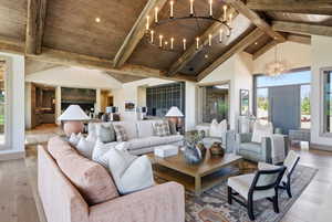 Living area featuring a vaulted wood-beam ceiling with wood-finish planks, a large circular chandelier, and light wood-finish flooring