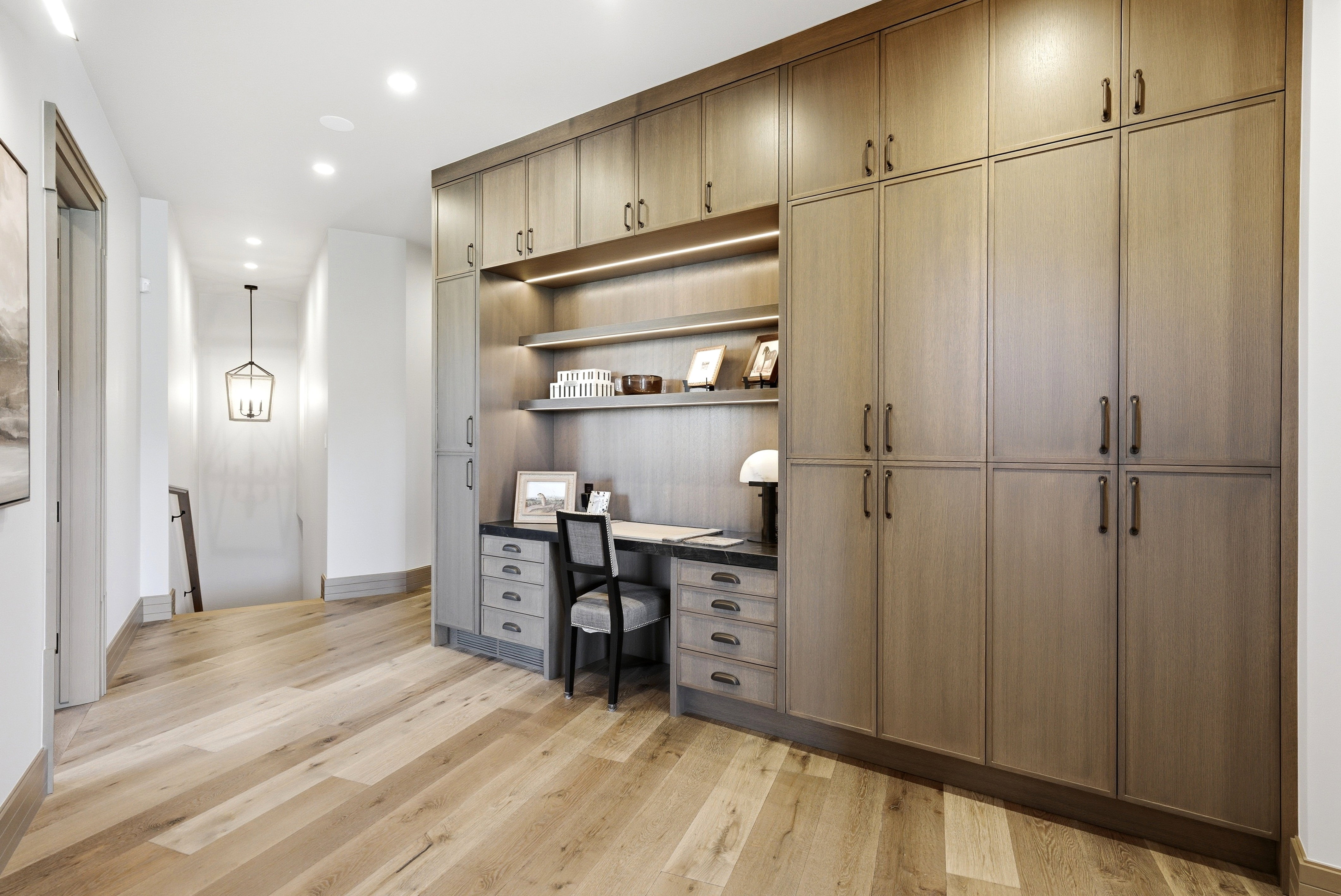 Built-in desk area with integrated shelving and task lighting, complemented by extensive full-height cabinetry