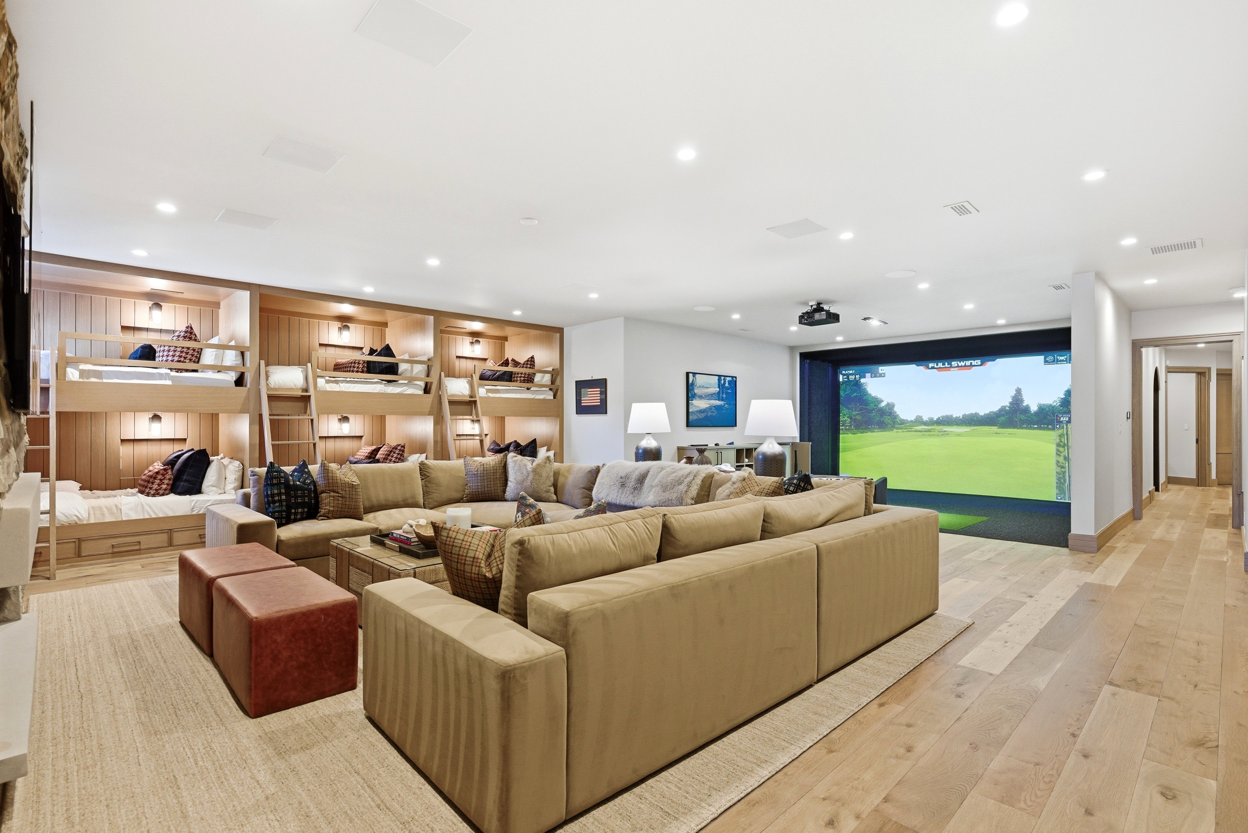 Recreation room featuring a large projection screen, built-in bunk beds with individual lighting, recessed ceiling lights, and light wood-finish flooring