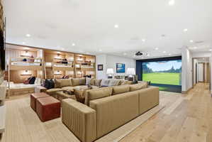 Recreation room featuring a large projection screen, built-in bunk beds with individual lighting, recessed ceiling lights, and light wood-finish flooring