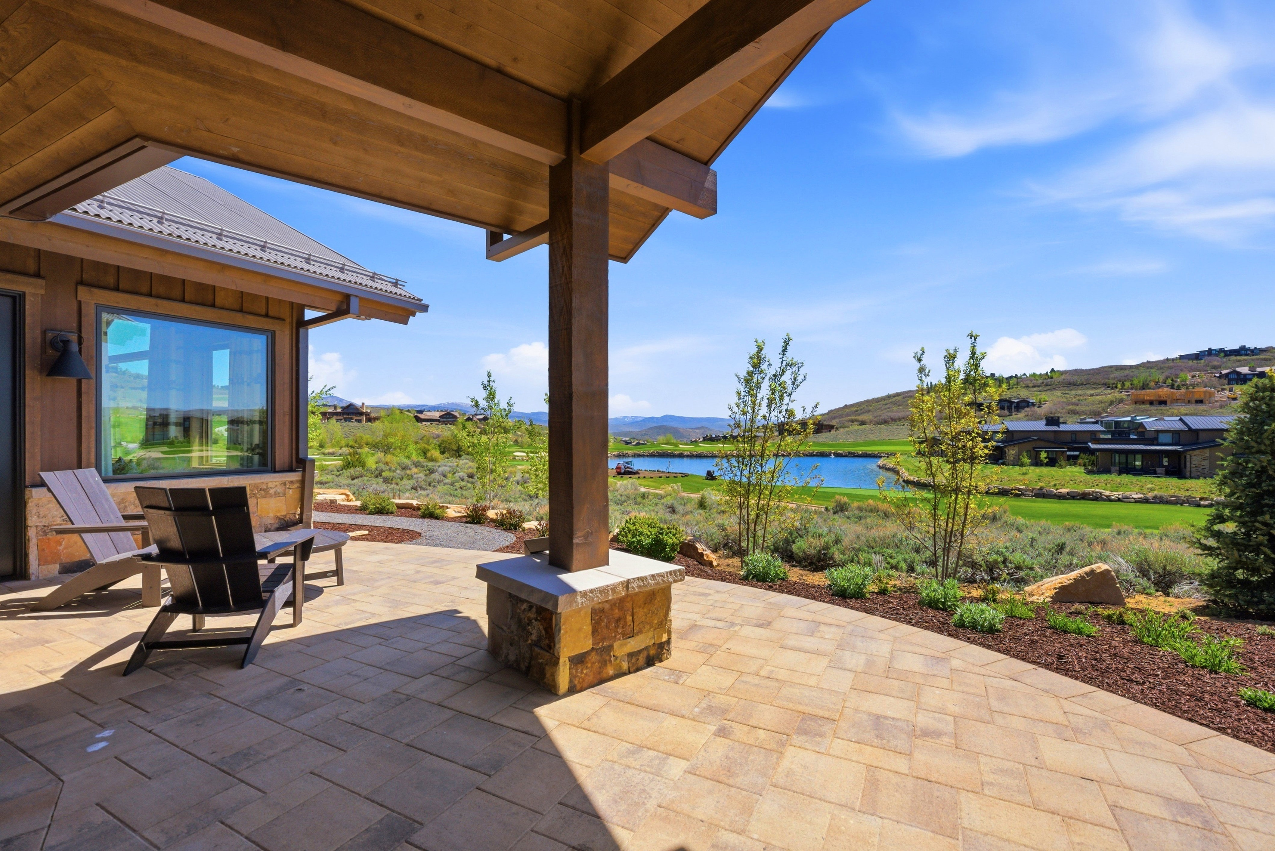 Paved outdoor patio featuring a wood-finish ceiling, stone pillar base, and a metal roofline