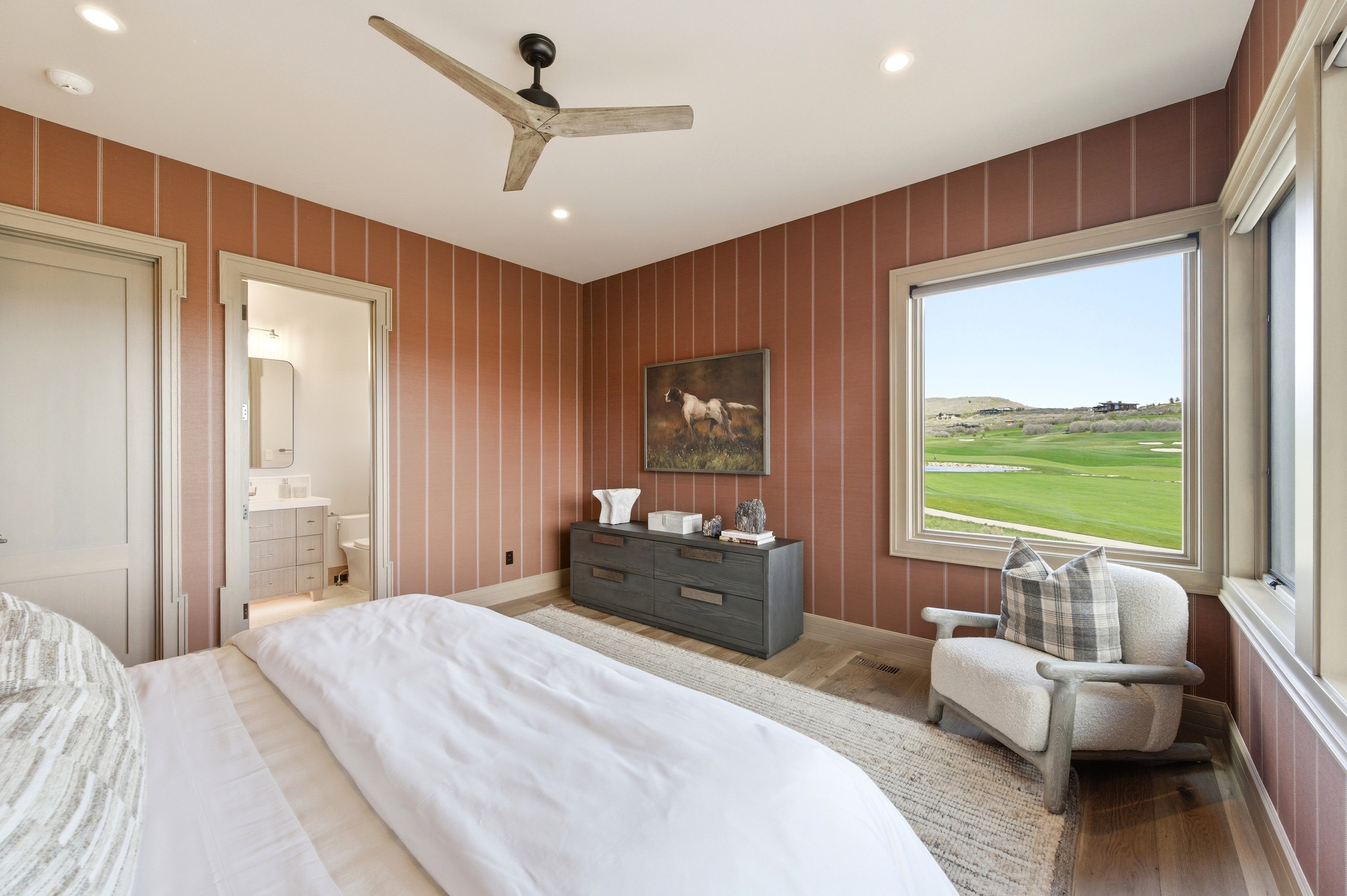 Spacious room featuring striped accent walls, wood-finish flooring, and a ceiling fan with integrated lighting