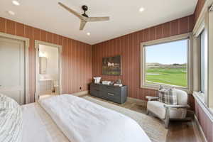 Spacious room featuring striped accent walls, wood-finish flooring, and a ceiling fan with integrated lighting