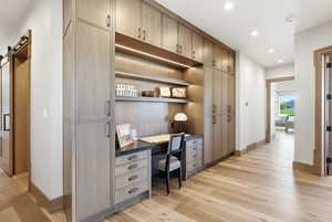 Built-in desk area featuring integrated shelving, recessed lighting, ample cabinet storage, and dark countertop surfaces