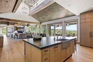 Spacious kitchen featuring a large island with an integrated farmhouse sink, wood-finish cabinetry, and dark countertops