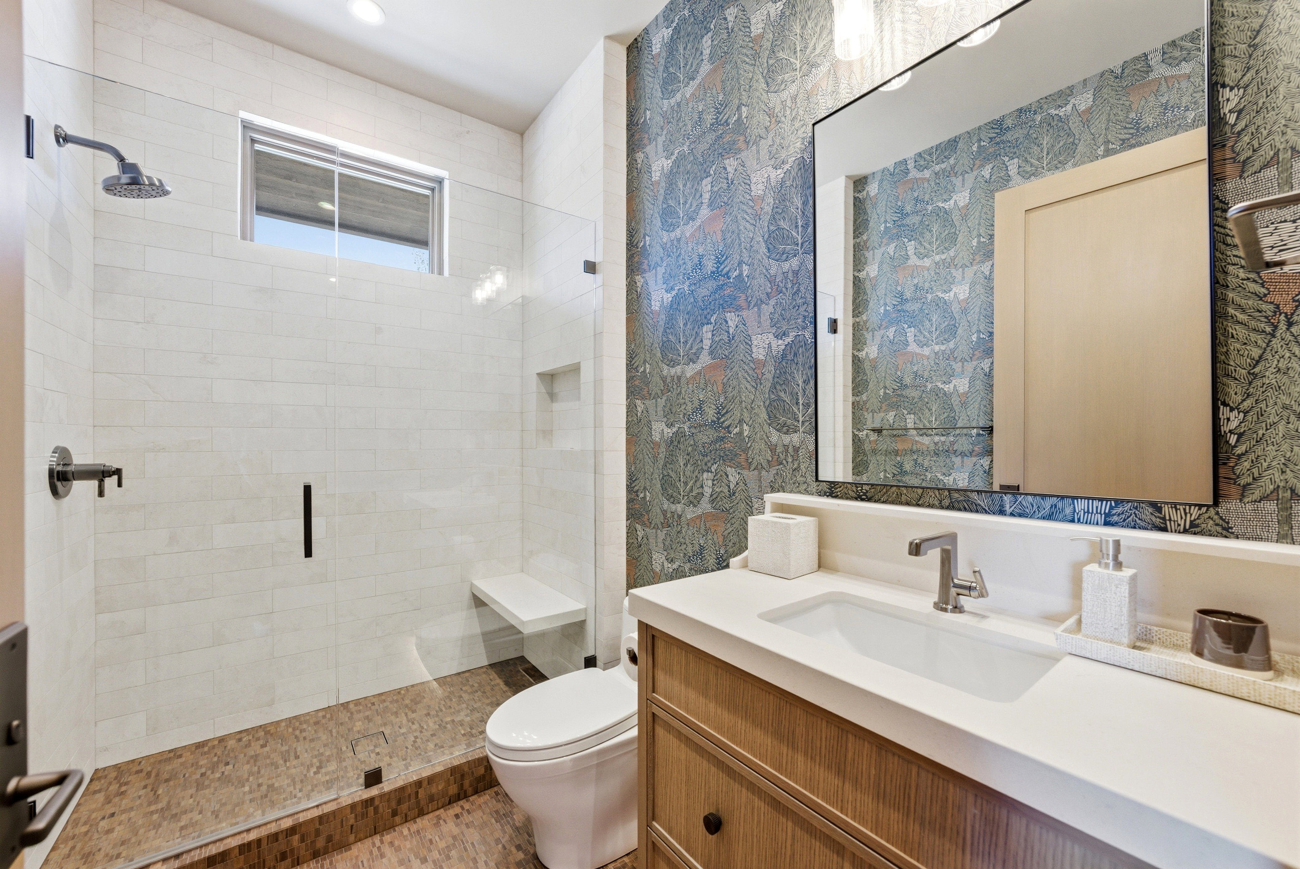 Bathroom featuring a glass-enclosed shower with white subway tile, a built-in shower bench, and a rectangular window