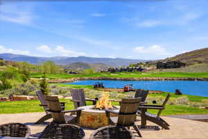 Expansive paver patio featuring a built-in stone fire pit, bordered by a manicured lawn
