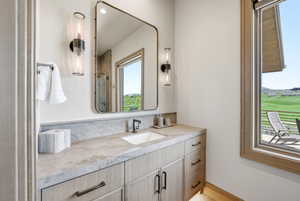 Bathroom vanity with a light wood-finish cabinet and integrated sink, complemented by a light-toned countertop and backsplash