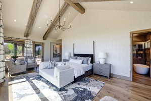 Vaulted ceiling featuring exposed wood beams and a chandelier