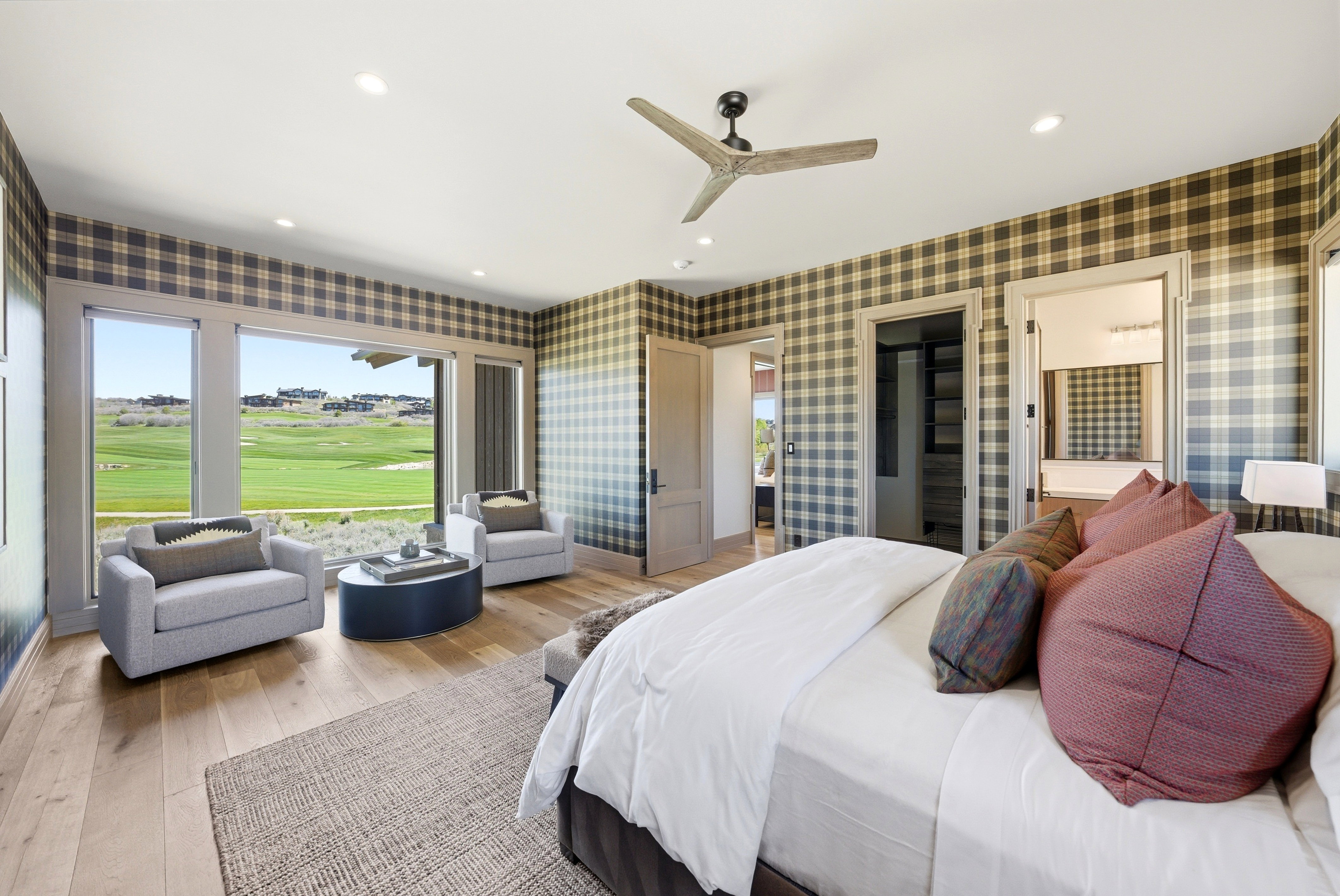 Spacious room featuring large picture windows with a golf course backdrop, wood-finish flooring, a contemporary ceiling fan, recessed lighting, and plaid wallpaper accents