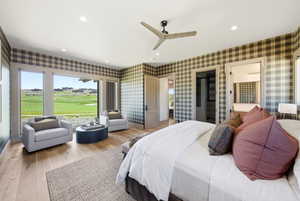 Spacious room featuring large picture windows with a golf course backdrop, wood-finish flooring, a contemporary ceiling fan, recessed lighting, and plaid wallpaper accents