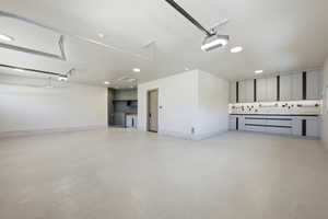 Spacious garage featuring light-colored flooring, recessed lighting, and ample built-in cabinetry with dark accents