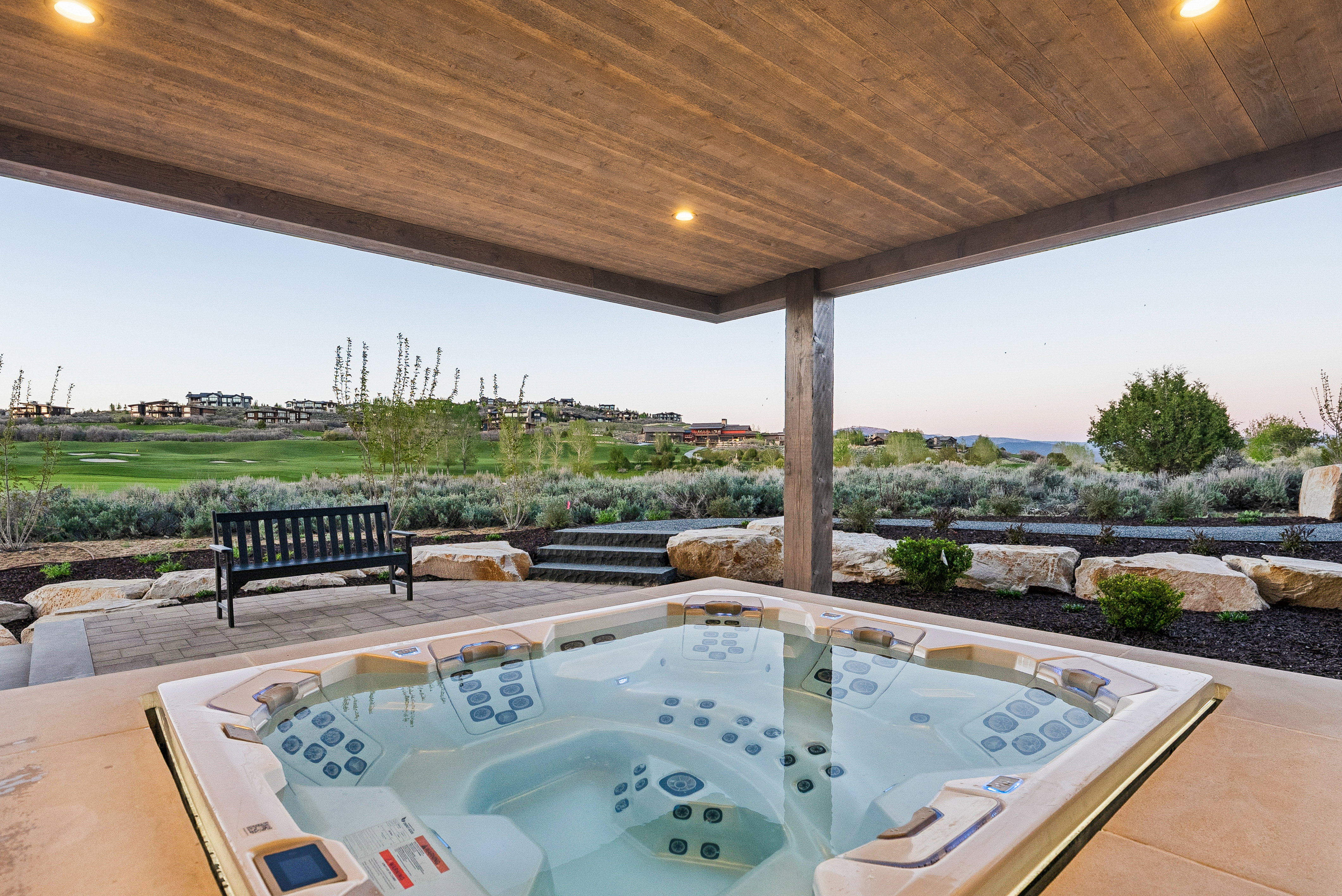Outdoor spa under a wood-finish covered patio with recessed lighting