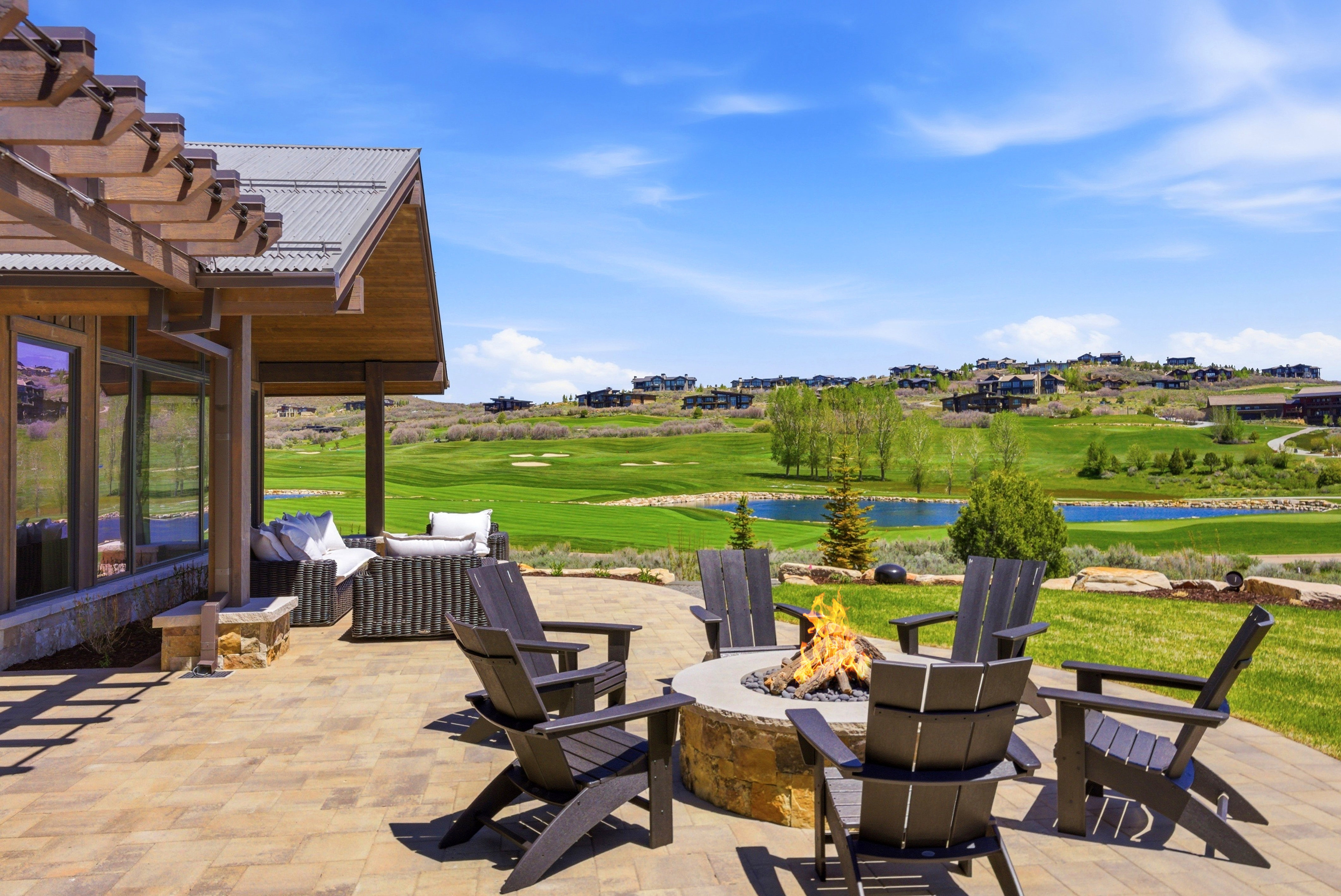 Expansive paver patio featuring a stone fire pit, covered outdoor living area, and wood pergola
