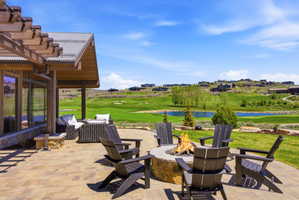 Expansive paver patio featuring a stone fire pit, covered outdoor living area, and wood pergola