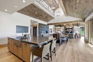 Spacious open-concept living area featuring a vaulted ceiling with exposed wood beams and recessed lighting
