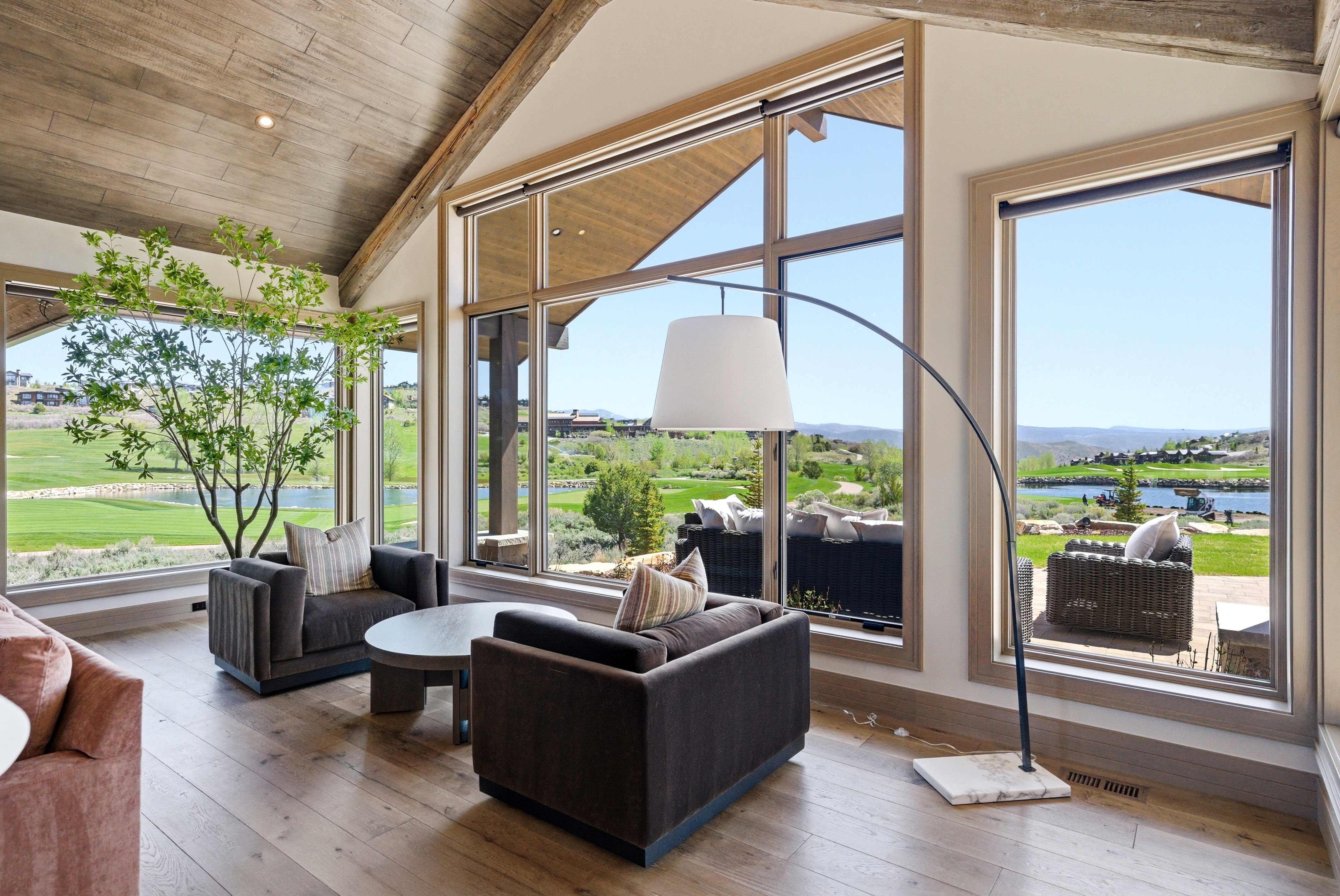 Living space featuring expansive windows, wood-finish flooring, vaulted wood plank ceilings with exposed beams, and a built-in recessed lighting fixture