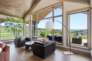 Living space featuring expansive windows, wood-finish flooring, vaulted wood plank ceilings with exposed beams, and a built-in recessed lighting fixture