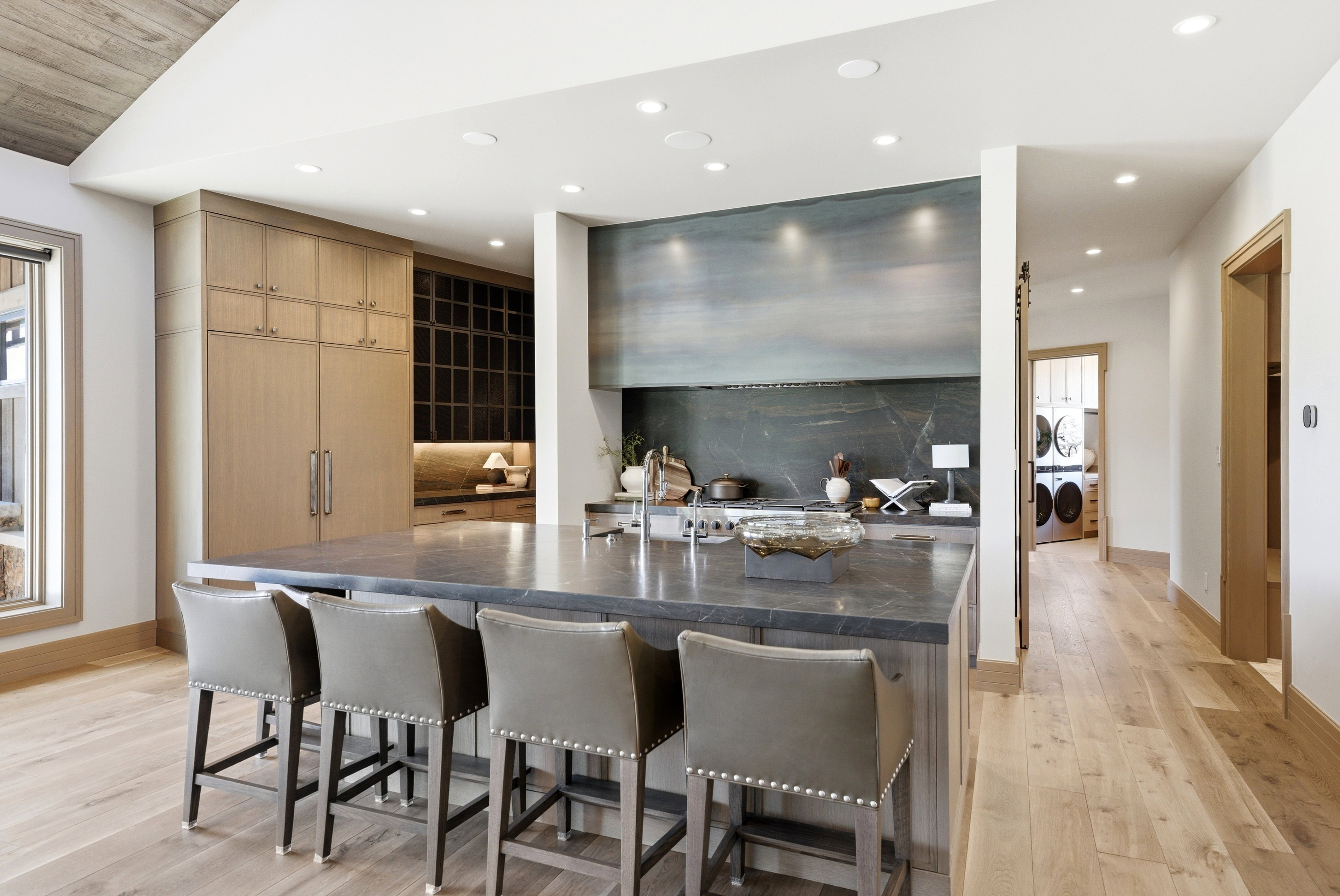 Gourmet kitchen featuring a large central island with seating, a professional-grade range, full-height cabinetry, wood-finish flooring, and recessed lighting
