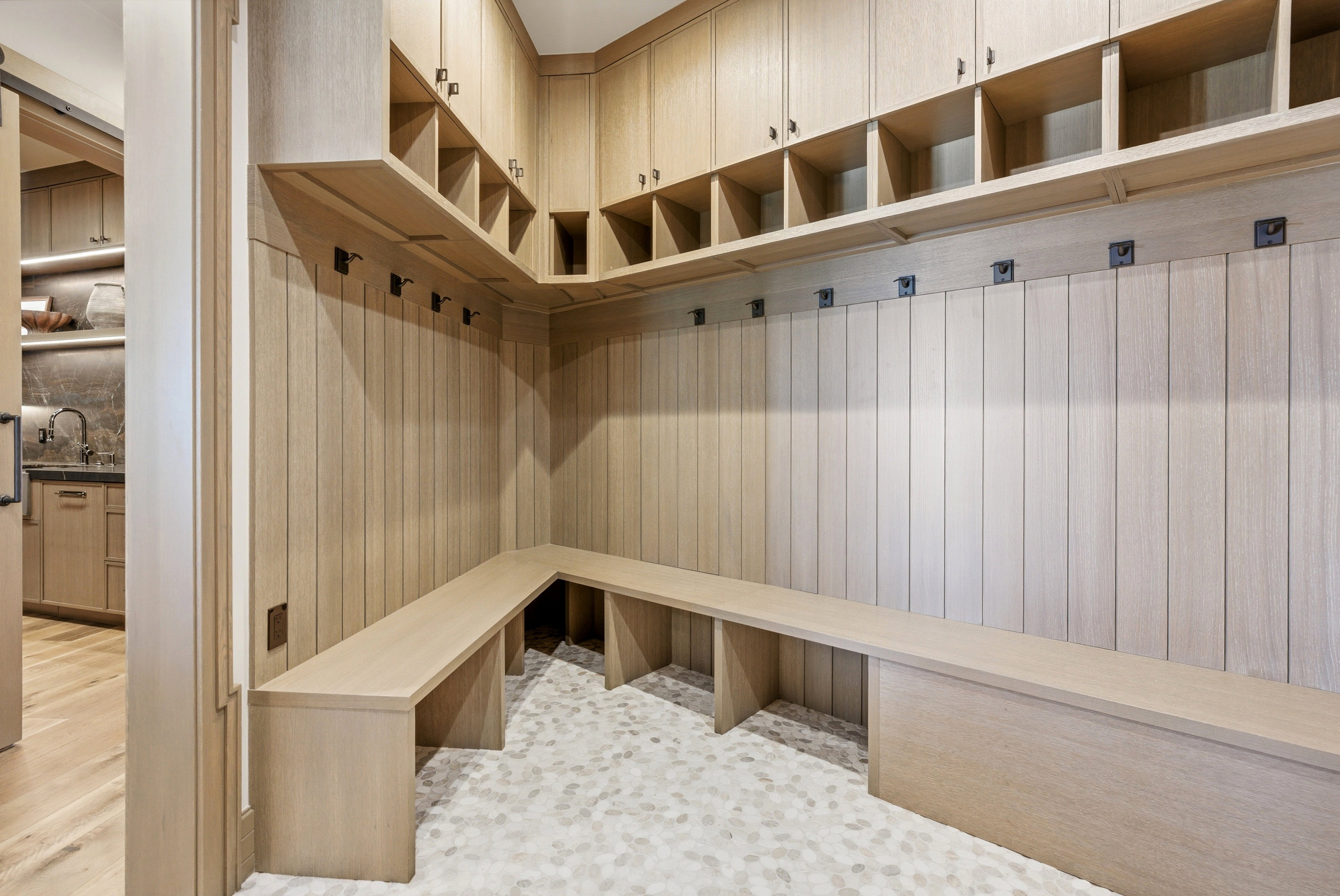 Mudroom with built-in bench seating, wood-finish paneling, and upper cabinetry storage