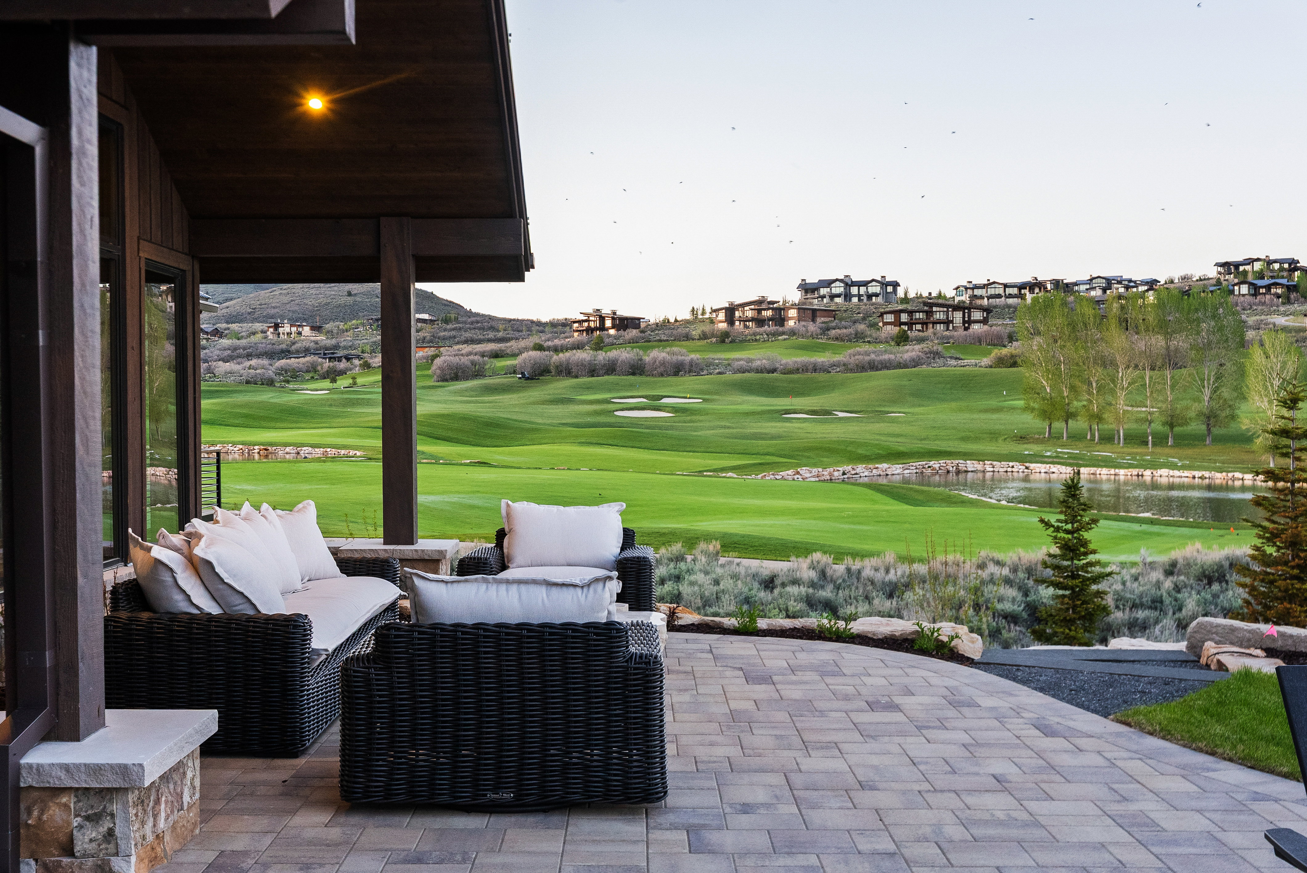 Expansive paver patio with a covered outdoor living area and stone pillar accents