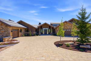 Stone and wood-sided exterior featuring multiple attached garages with wood-finish doors