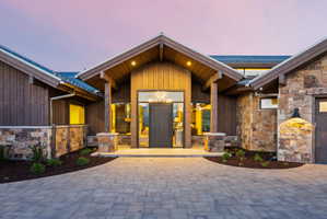 Contemporary exterior with a prominent A-frame entrance, featuring a paver driveway, stone veneer accents, wood siding, and recessed lighting