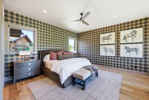 Spacious bedroom featuring plaid wall covering, wood-finish flooring, a ceiling fan, recessed lighting, and multiple windows