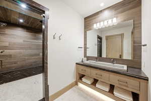 Wood-finish tile shower with a dark stone bench and light tile flooring