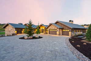 Stone and wood-sided exterior featuring multiple garage bays and a paver driveway