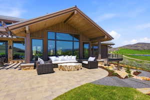 Expansive outdoor patio featuring a large paver surface, stone accent walls, and a wood-paneled ceiling
