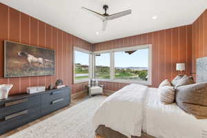 Spacious bedroom featuring striped wall covering and light wood-finish flooring