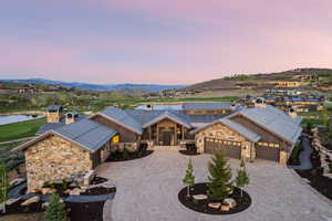 Expansive stone and wood-clad exterior with a multi-car garage, large driveway, and landscaped grounds