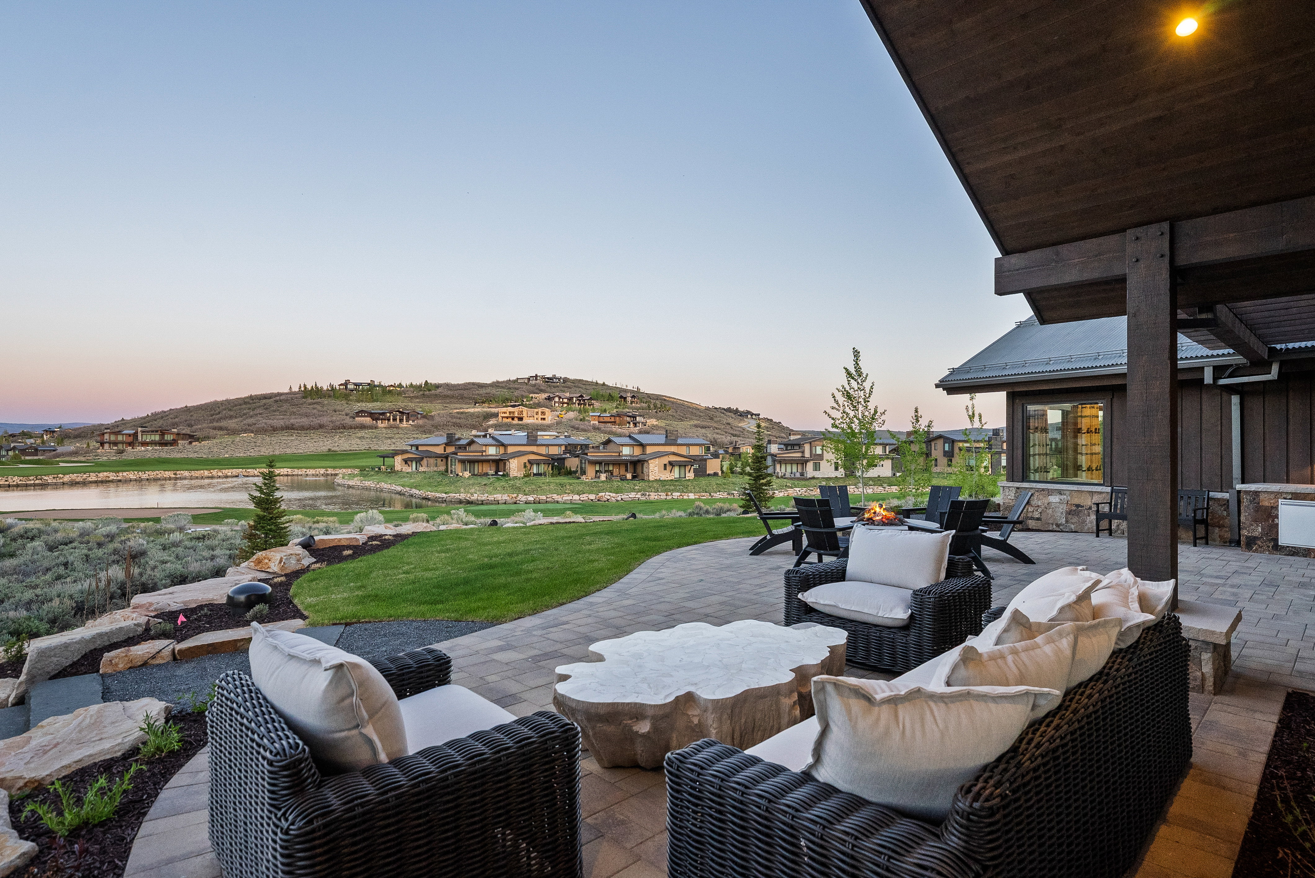 Spacious outdoor patio featuring paver stone flooring, a built-in outdoor kitchen area, and a stone fire pit