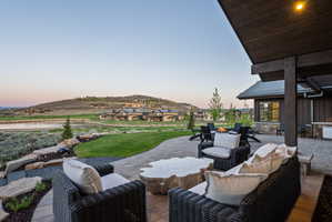 Spacious outdoor patio featuring paver stone flooring, a built-in outdoor kitchen area, and a stone fire pit