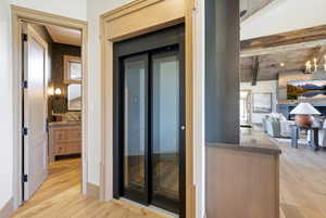 Integrated residential elevator with clear glass doors, flanked by light wood-finish trim
