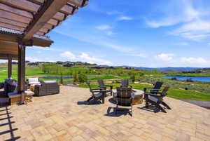 Expansive paver patio featuring a built-in stone fire pit and a covered pergola