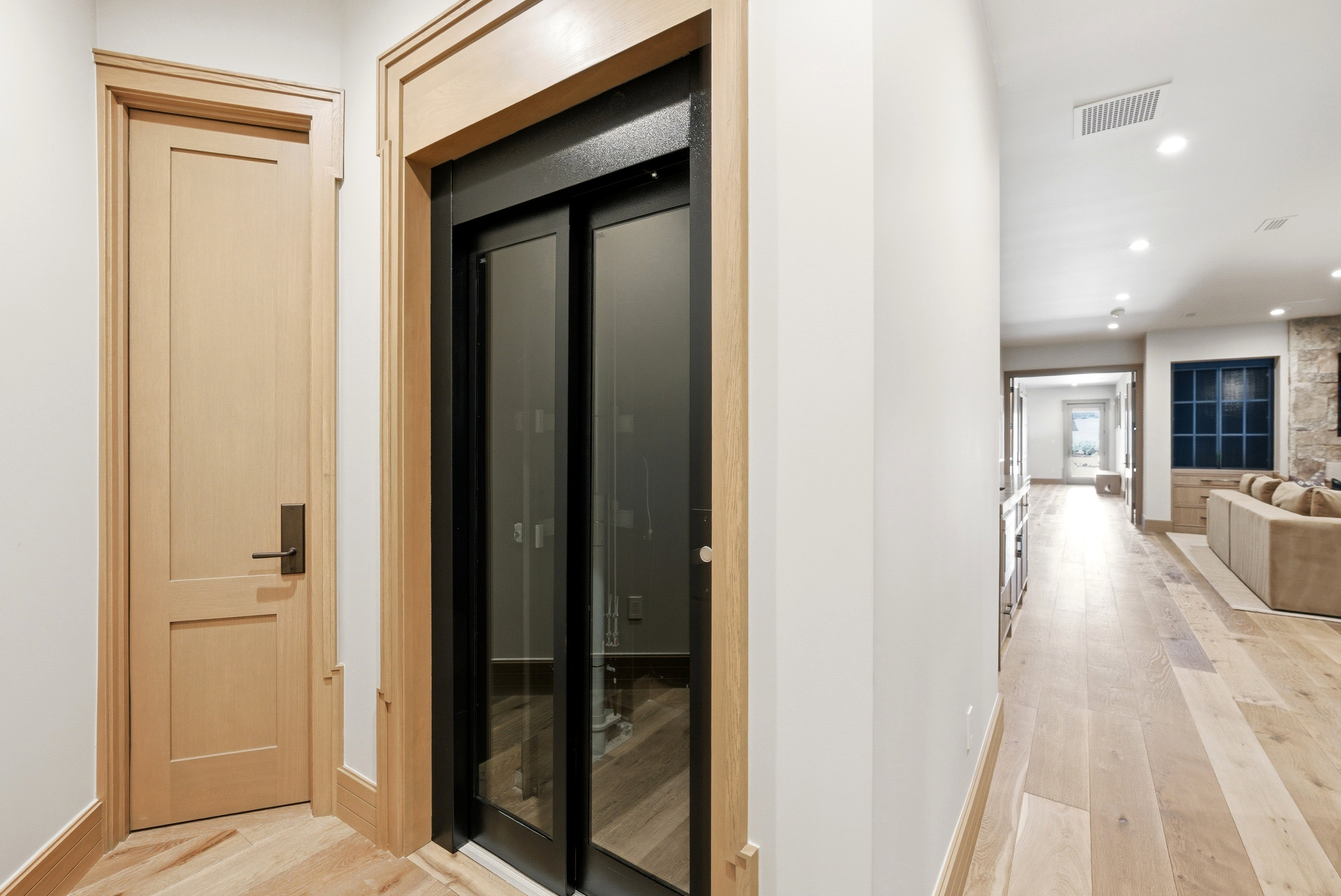 Integrated glass-paneled elevator with natural wood-finish trim