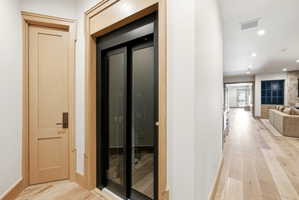 Integrated glass-paneled elevator with natural wood-finish trim