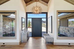Grand entry featuring a vaulted wood-beam ceiling and a large decorative chandelier