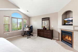 Vaulted ceiling room featuring an arched window, three additional windows, a built-in fireplace with a tile surround, and an integrated media niche