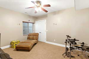 Carpeted room featuring a ceiling fan with light fixture, recessed window with blinds, white paneled door, and neutral wall tones
